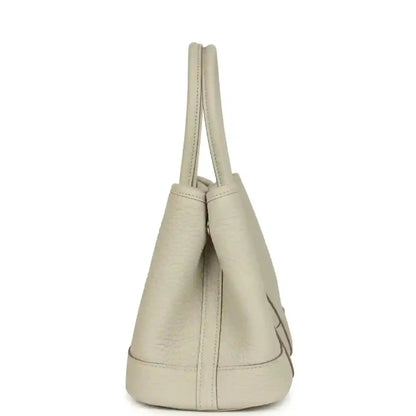 Hermes Garden Party Neo 23 tote bag side view in light beige leather with short handles and curved base