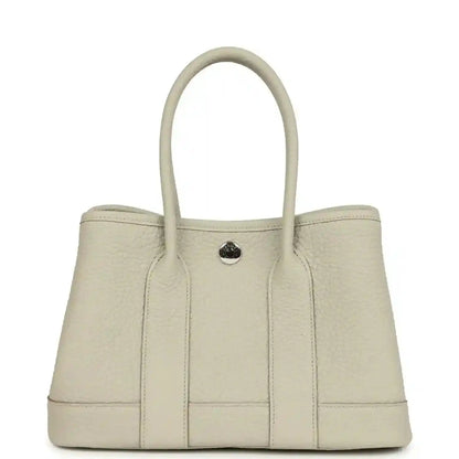 Hermes Garden Party Neo 23 tote bag front view in light beige leather with round front clasp