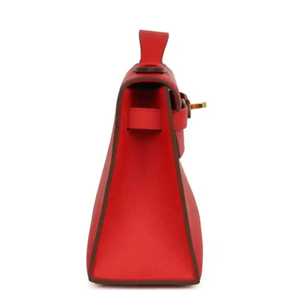 Red leather pochette with open interior, side strap, and gold buckle