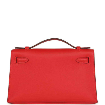 Red leather pochette back view with two embossed strap tabs and top handle