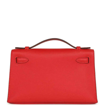 Red leather pochette back view with two embossed strap tabs and top handle
