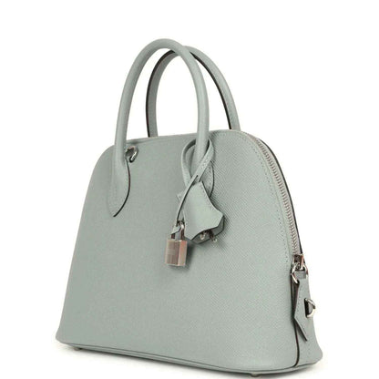 Light gray leather handbag angled side view with zipper pocket and silver-tone zipper pulls