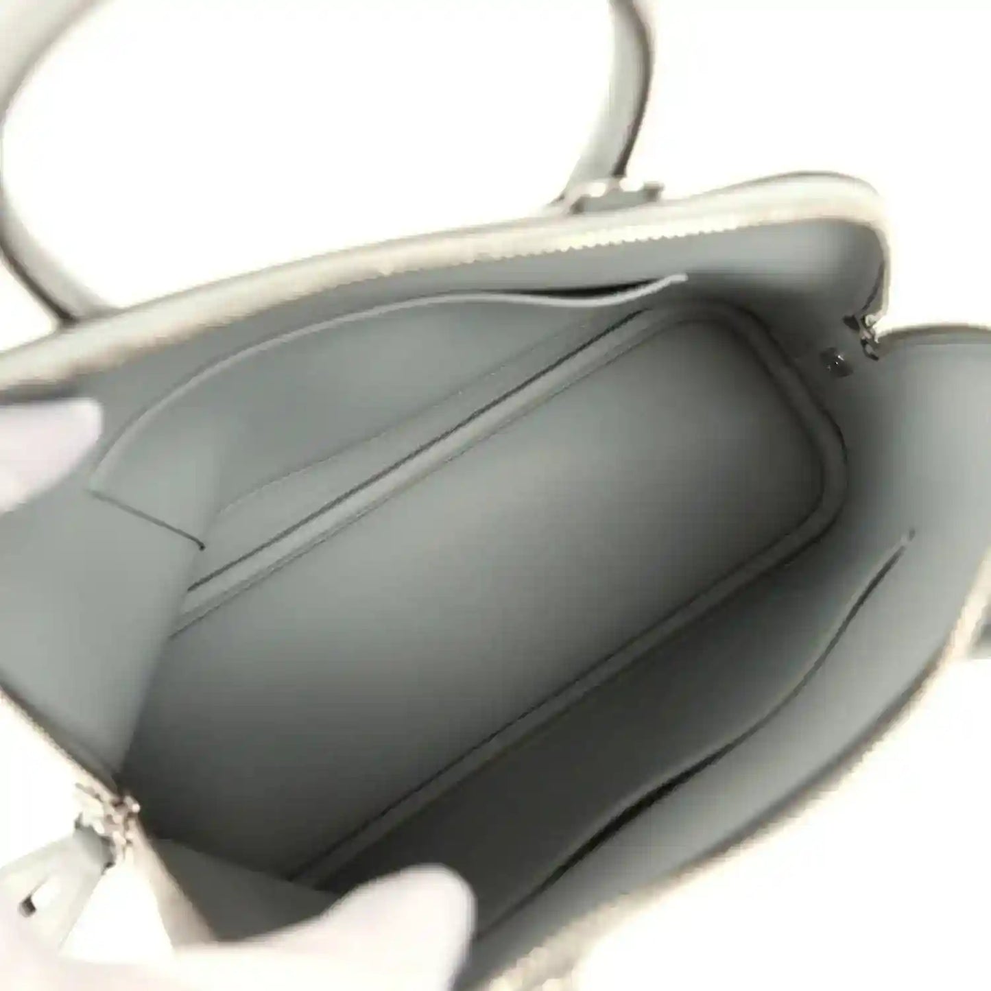 Light gray leather handbag interior with dark lining and open top zipper opening