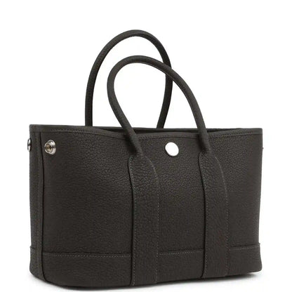 Leather tote bag with top handles, front panel pockets and small metal snap