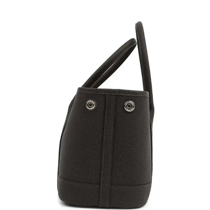 Leather tote bag side view with dual handles and two metal snap buttons