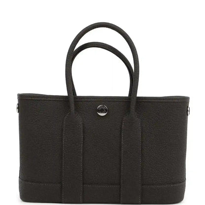 Leather tote bag with top handles and three front vertical panels, center snap