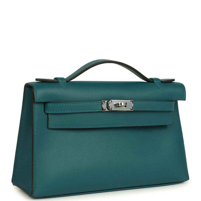 Teal green leather top-handle bag with front flap and silver-toned clasp, angled view.