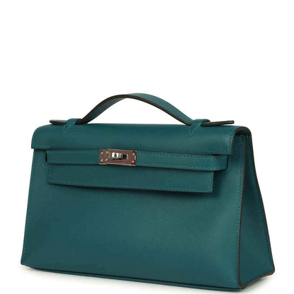 Teal green leather handbag with front flap and silver-toned clasp, three-quarter view.