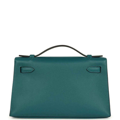 Teal green leather handbag with top handle and stitched corner tabs, back view.