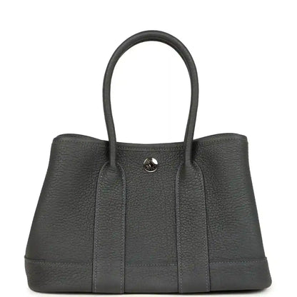 Dark gray leather tote bag with top handles and round front logo clasp