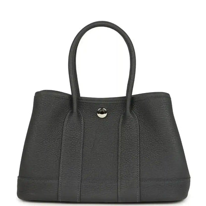 Dark gray leather tote bag with top handles and centered round front clasp