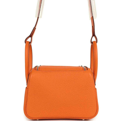 Orange structured leather mini shoulder bag with flap top and top carry handles.