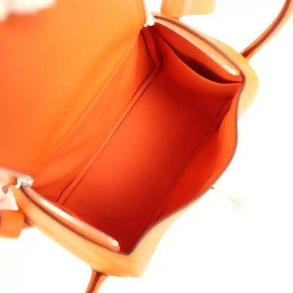Orange leather mini handbag interior with lined cavity and top opening under strap.