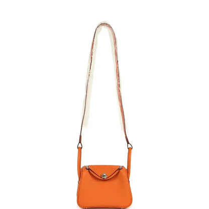 Orange leather mini crossbody bag with long strap and small flap closure.
