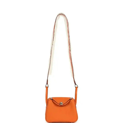 Orange leather mini crossbody bag with long strap and small flap closure.