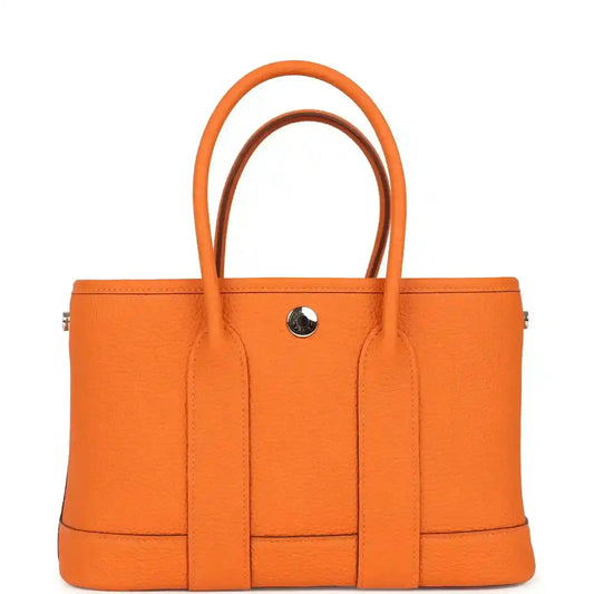 Orange leather tote bag with central divider and snap button hardware