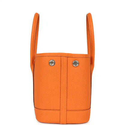 Orange leather mini tote bag with two top handles and vertical seams