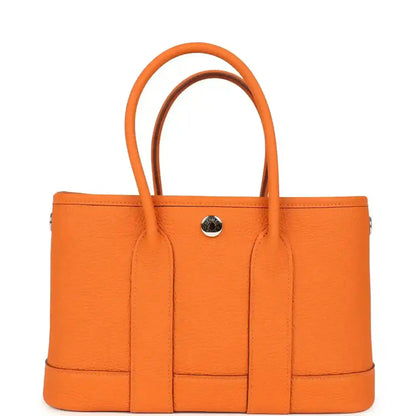 Orange leather tote bag with curved handles and round snap hardware