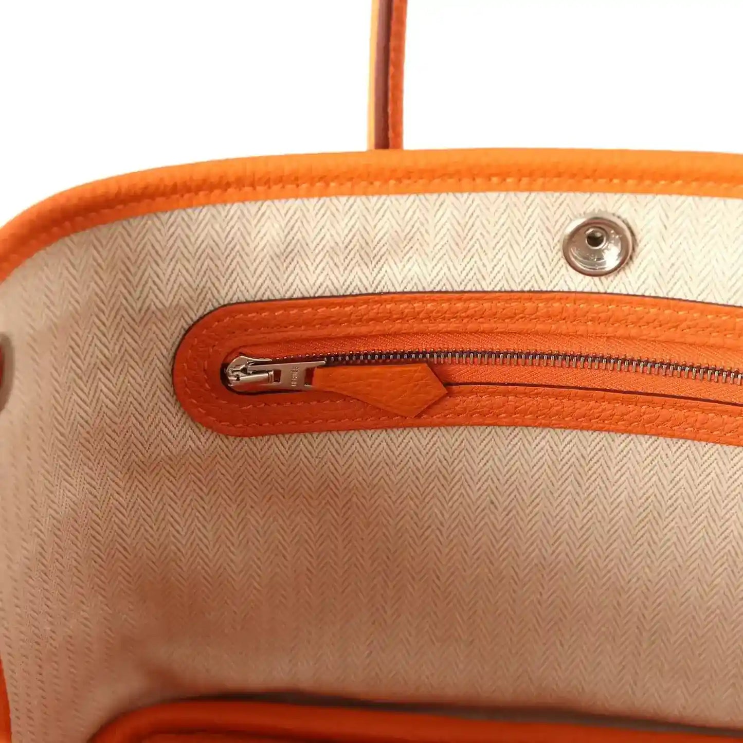 Orange leather zipper compartment with silver zipper pull on beige lining