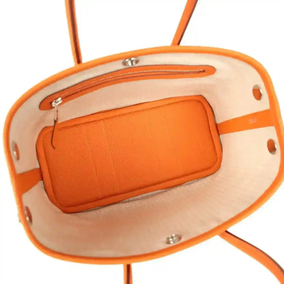 Orange leather-lined interior pocket with silver hardware inside tote bag