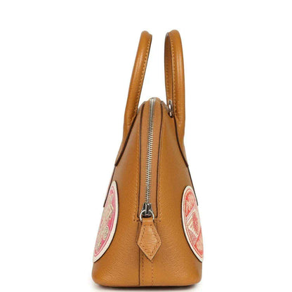 Mini tan leather handbag side view with zipper detail and hanging logo patch
