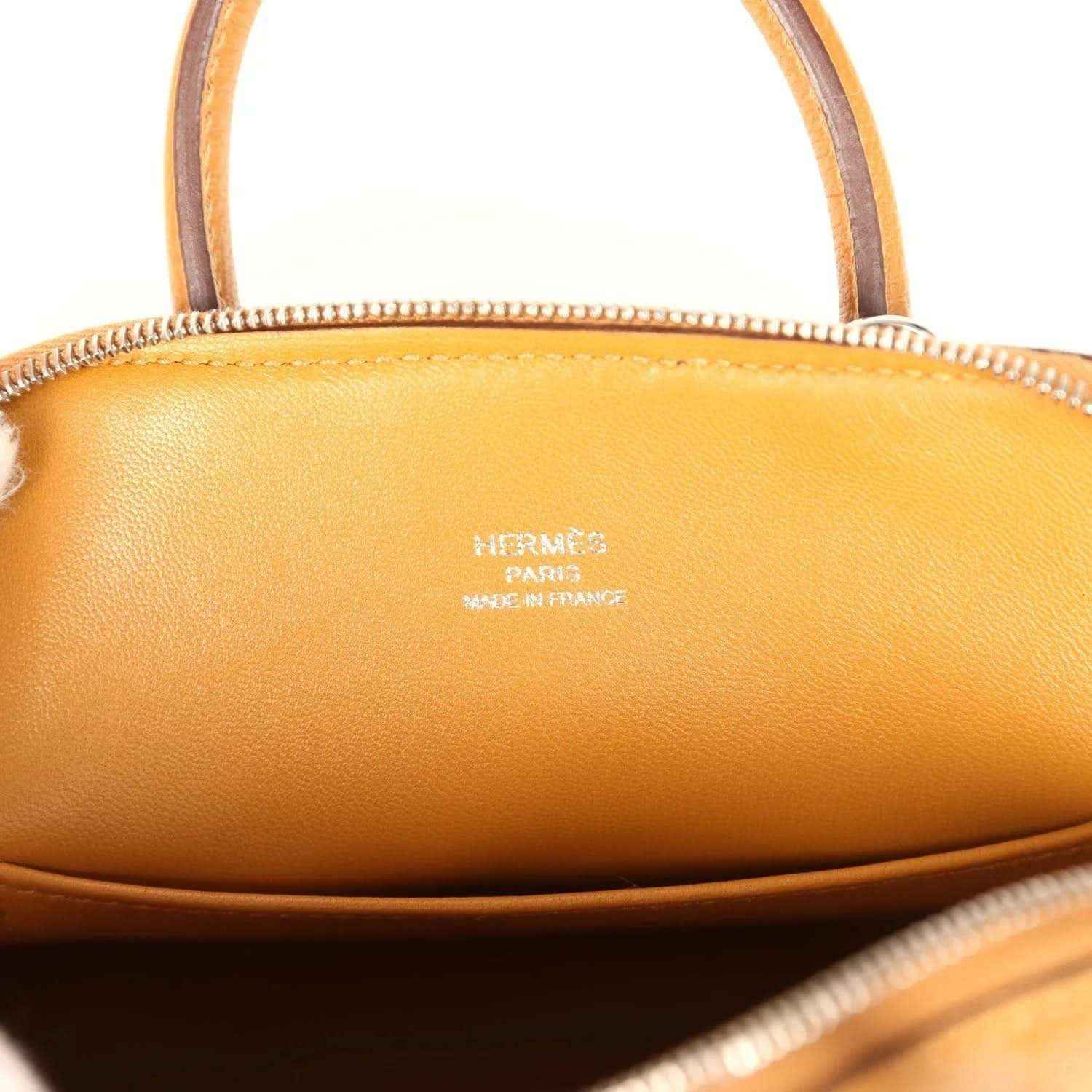 Mini handbag interior close-up with embossed brand stamp on tan leather