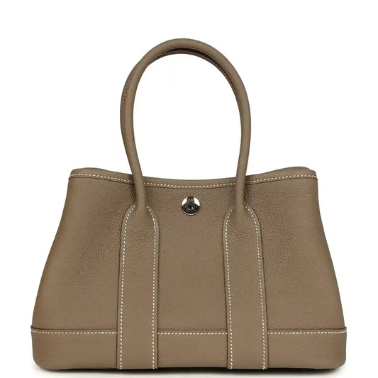 Taupe leather mini tote bag with two top handles and front snap pocket, stitched panels