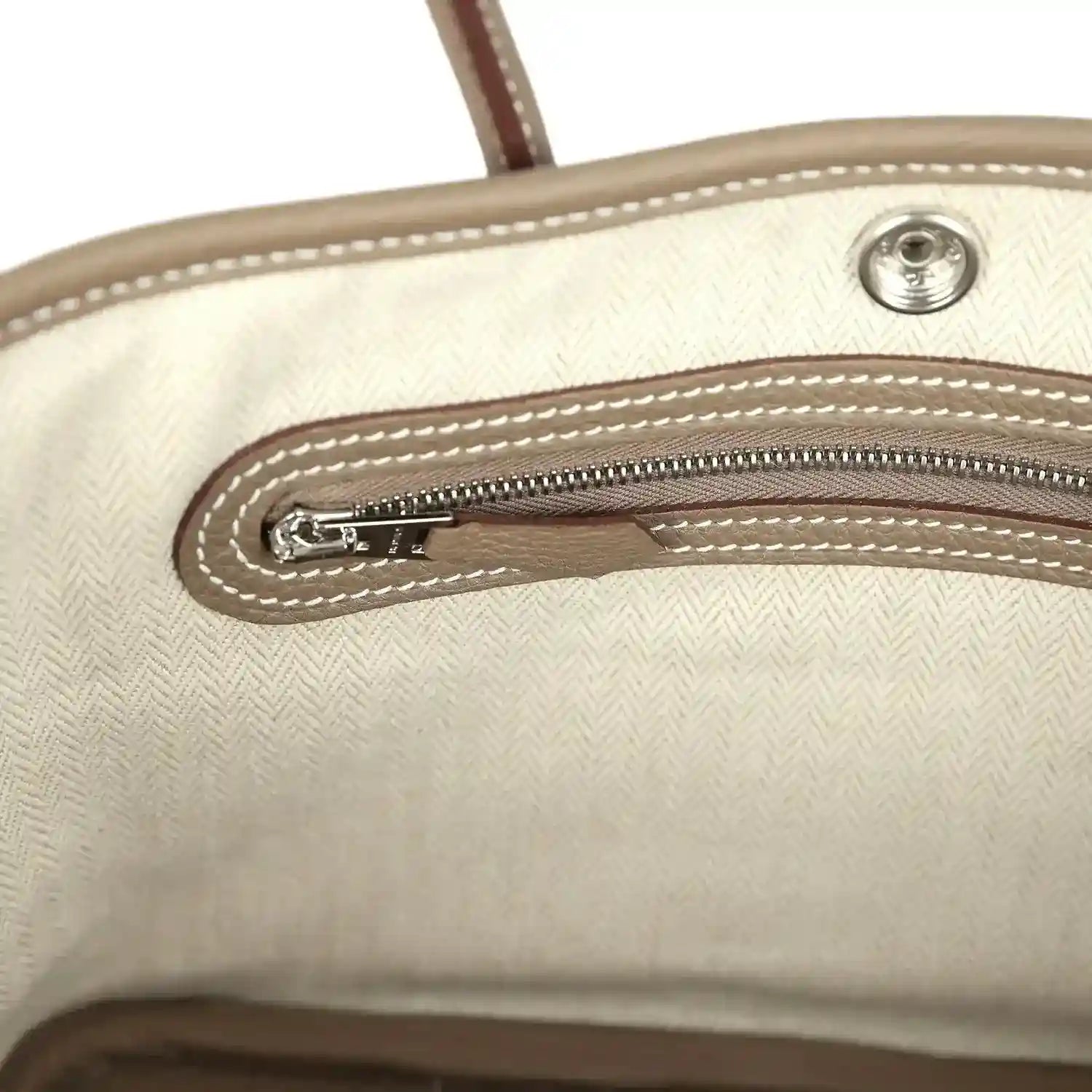 Light interior lining of mini tote bag with zipper and stitched edge detailing