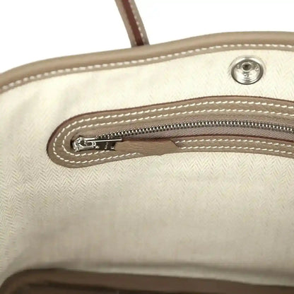 Light interior lining of mini tote bag with zipper and stitched edge detailing