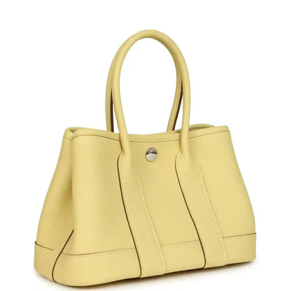 Yellow leather tote bag with top handles and front panel seams, snap button closure