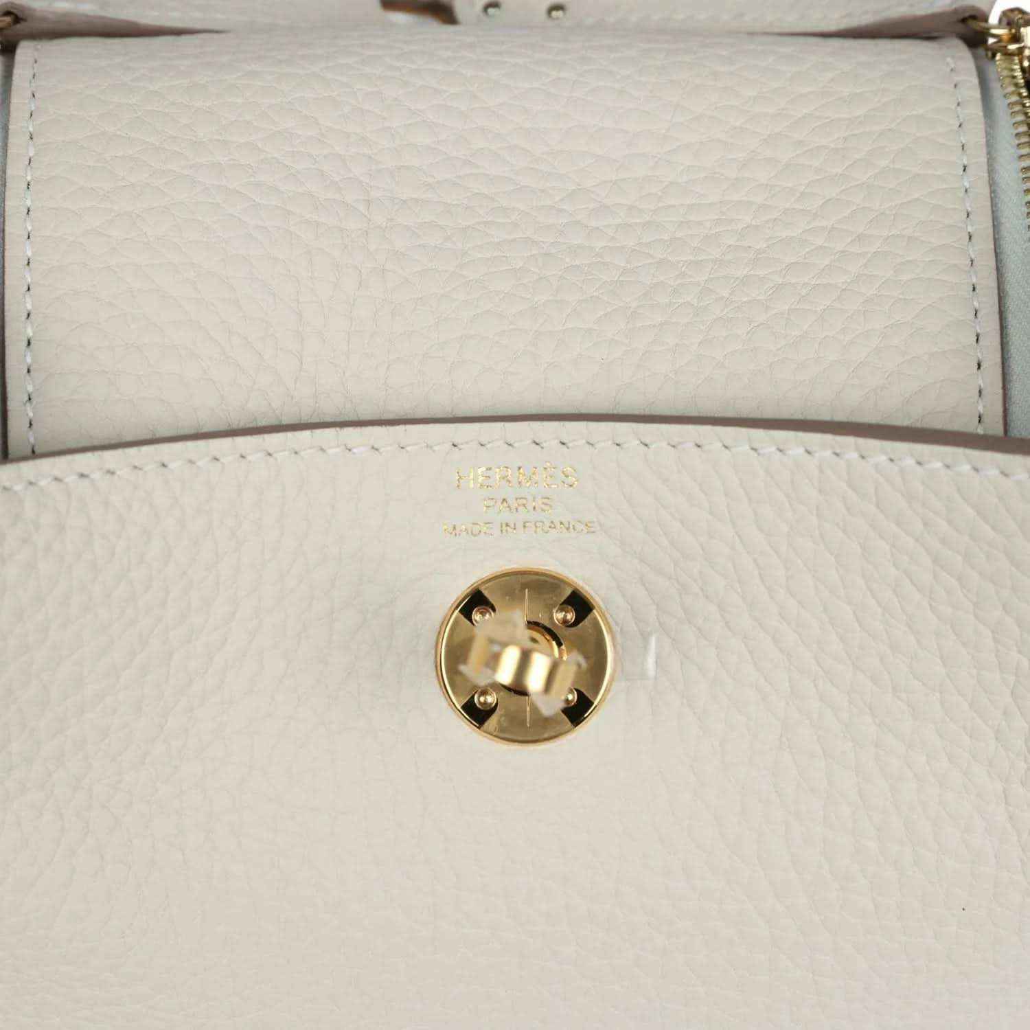 Mini Lindy II bag front flap close-up: gold turn-lock clasp on textured cream leather