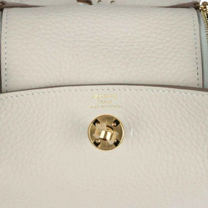 Mini Lindy II bag front flap close-up: gold turn-lock clasp on textured cream leather