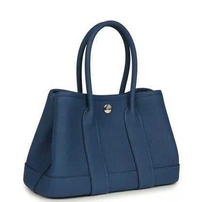 Blue leather tote with structured front panels and curved handles