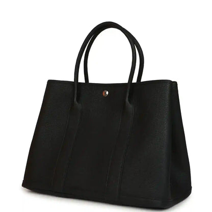Black leather tote bag with two top handles and gold-tone snap button