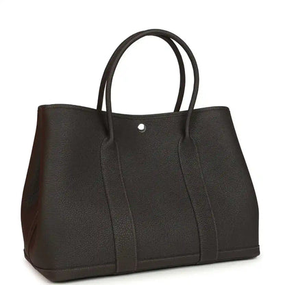 Leather tote bag with top handles, dark brown front with central vertical panels.
