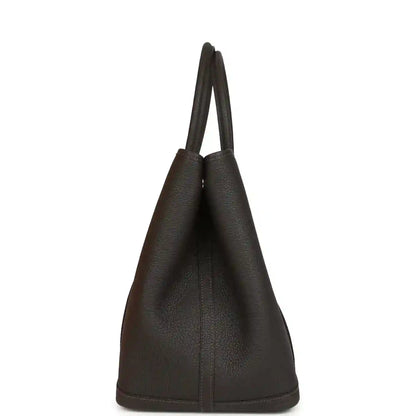 Leather tote bag side view with tall structure and top handles, dark brown.