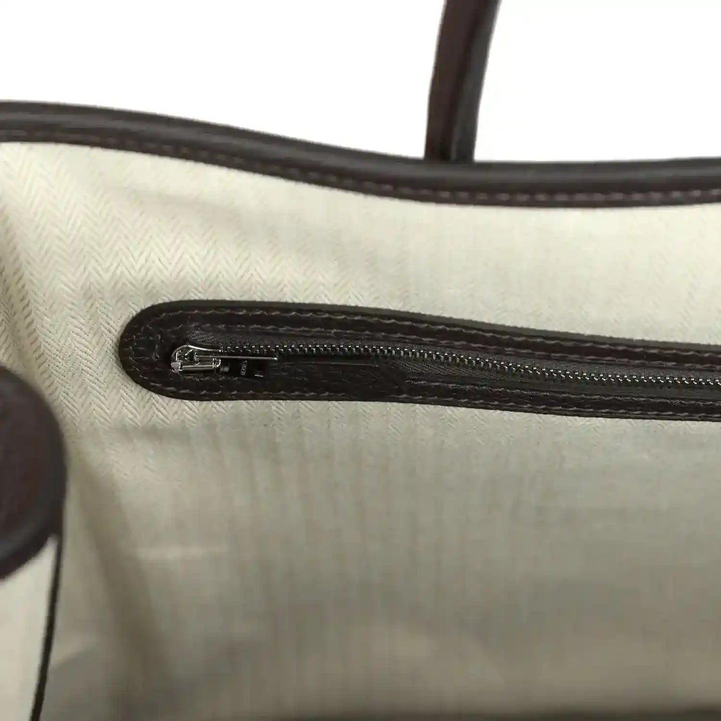 Leather pouch interior with stitched fabric lining and metal zipper track, dark brown edges.