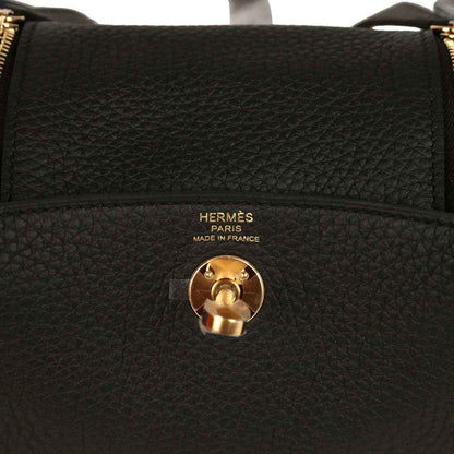 Hermes Mini Lindy II bag closeup: black textured leather with gold turn-lock and Hermes Paris text