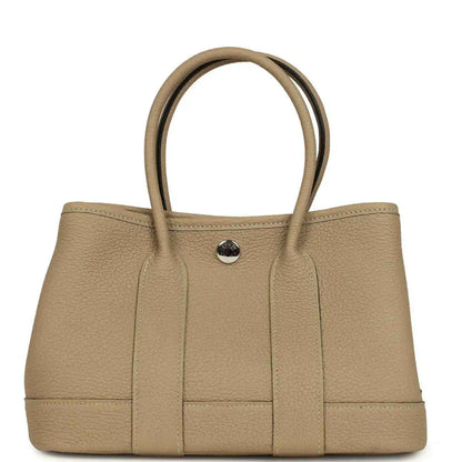 Trench leather tote with top handles and front button snap closure