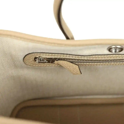 Trench leather tote zipper and metal pull on an interior pocket