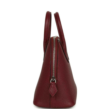 Mini leather handbag with zipper closure, top handles, and deep red leather