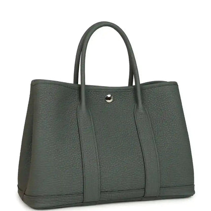 Leather tote bag with top handles and snap front tab, textured dark green exterior