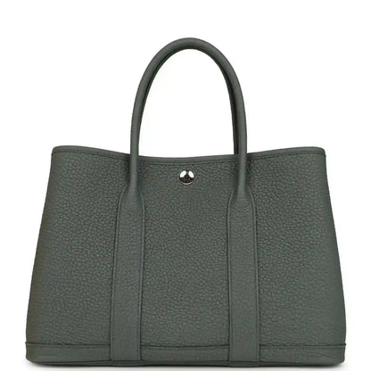 Leather tote bag with top handles and snap front tab, textured dark green