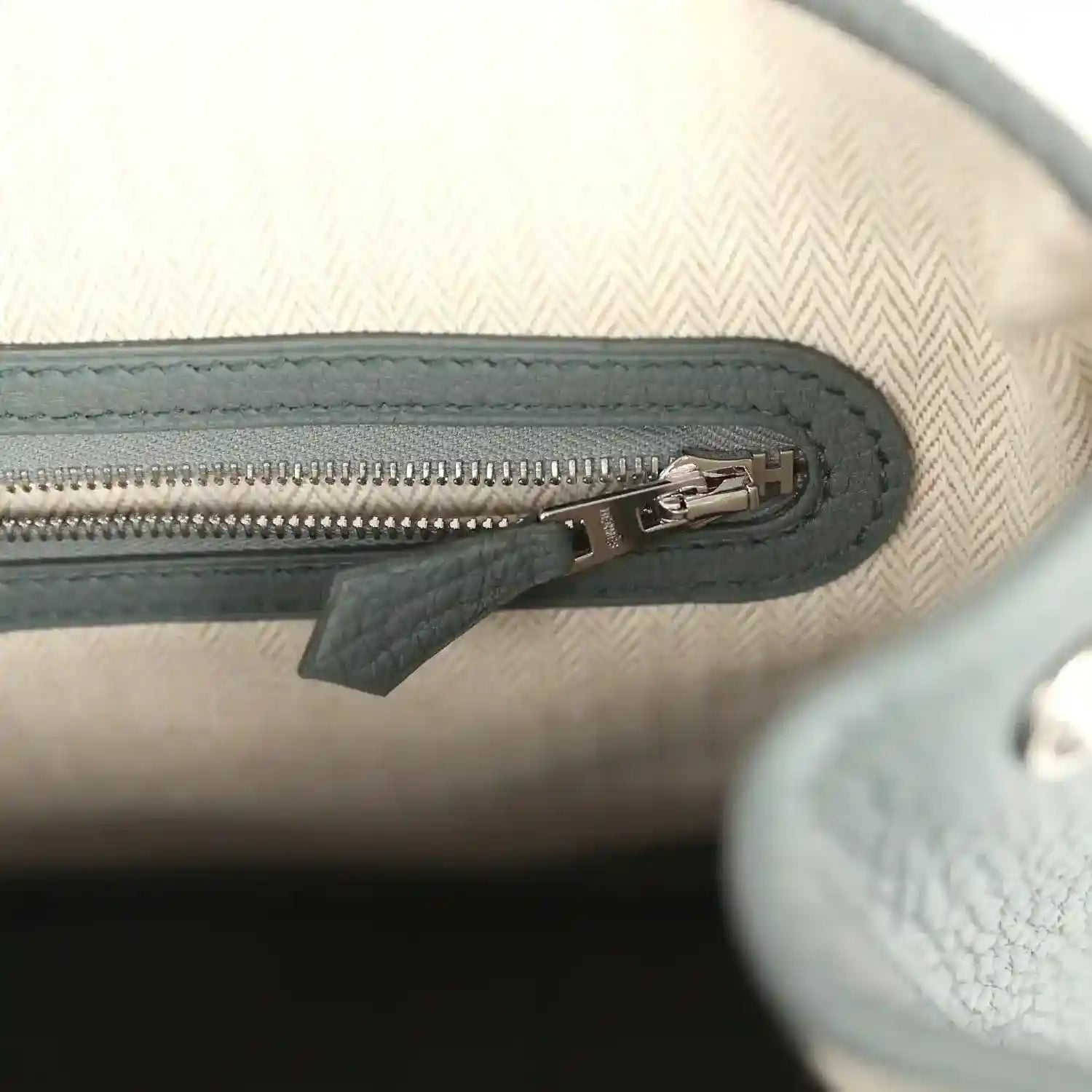 Leather tote interior zipper with metal pull, dark green trim on light lining