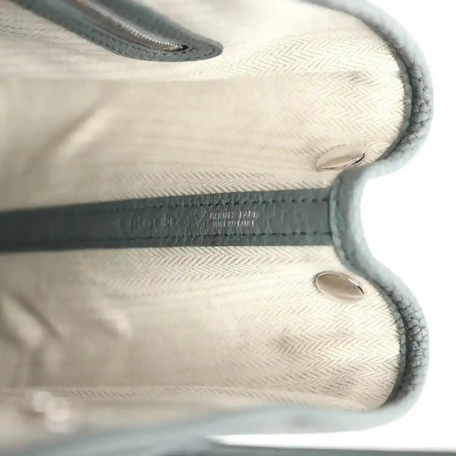 Leather tote interior with embossed logo detail and stitched edges, light lining