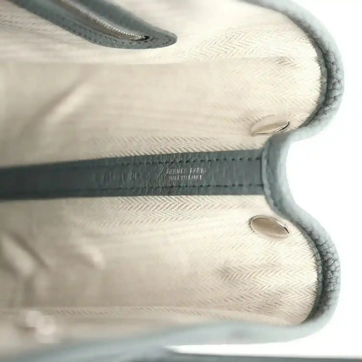 Leather tote interior with embossed logo detail and stitched edges, light lining
