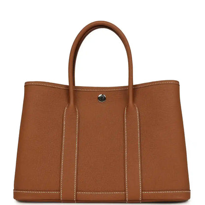 Brown leather tote bag with two top handles and a gold-tone snap on front