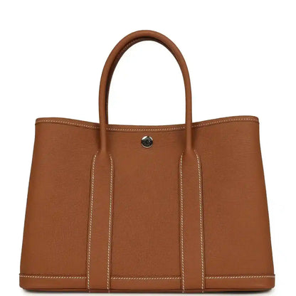 Brown leather tote bag with two top handles and a gold-tone snap on front