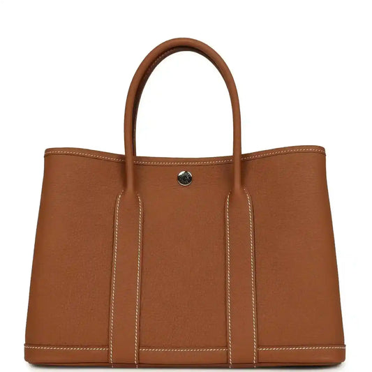 Brown leather tote bag with two top handles and a gold-tone snap on front