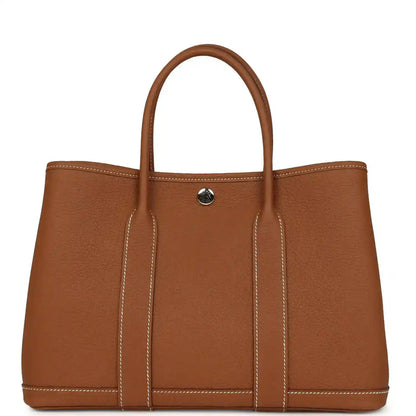 Brown leather tote bag with two top handles and gold-tone snap at center